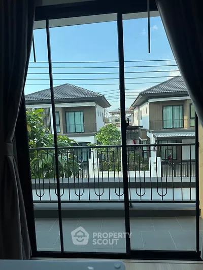 Charming balcony view of modern suburban homes with lush greenery and clear blue sky.