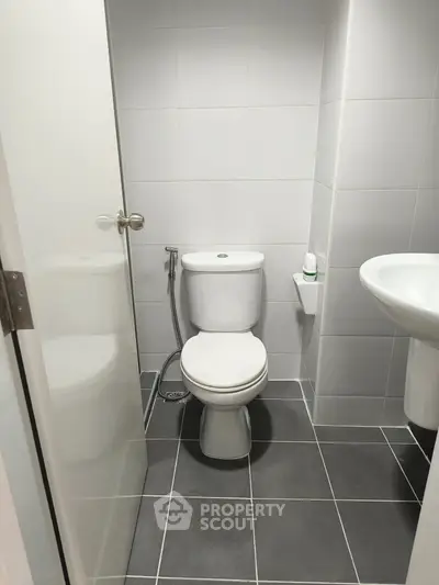 Modern bathroom with sleek white fixtures and tiled flooring, perfect for a contemporary home.