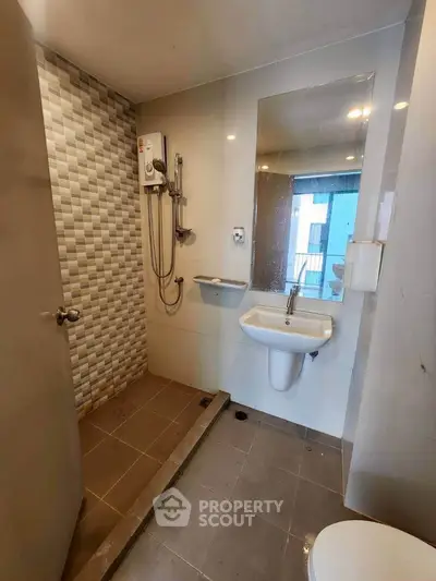 Modern bathroom with sleek design, featuring a shower, sink, and stylish tile accents.