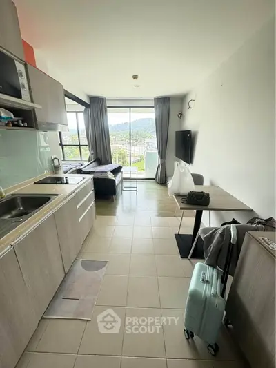 Modern open-layout apartment with kitchen and living area, featuring large windows and scenic views.