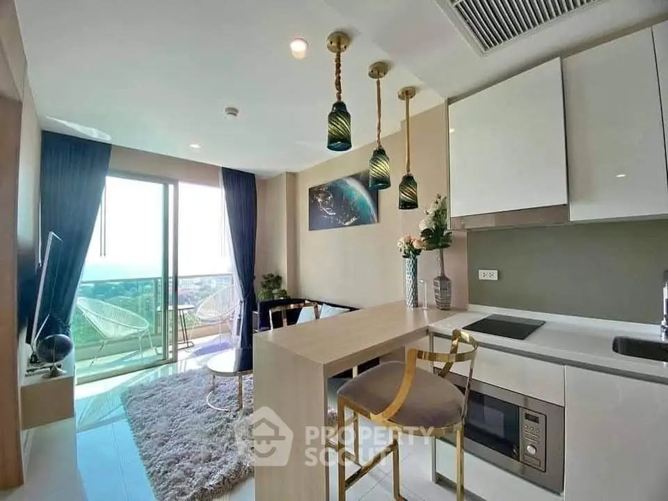 Modern kitchen with open layout and stylish decor, featuring a breakfast bar and balcony view.