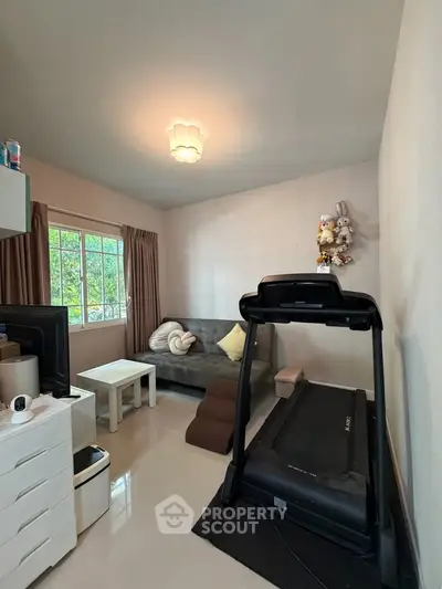 Cozy living room with treadmill and plush sofa, perfect for relaxation and fitness.