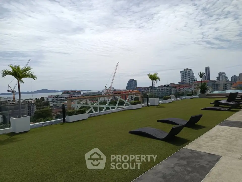 Stunning rooftop view with lounge chairs overlooking city skyline and ocean