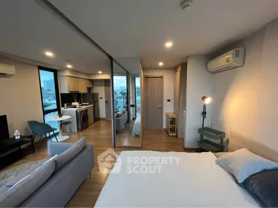 Modern open-plan studio apartment with kitchen, living area, and city view.