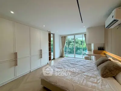 Spacious bedroom with large windows and balcony access, featuring modern decor and ample natural light.
