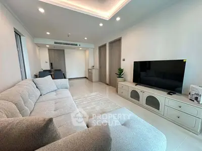 Spacious modern living room with plush sofa and large TV, perfect for relaxation and entertainment.