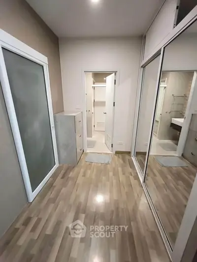 Spacious modern bedroom with mirrored closet and wooden flooring