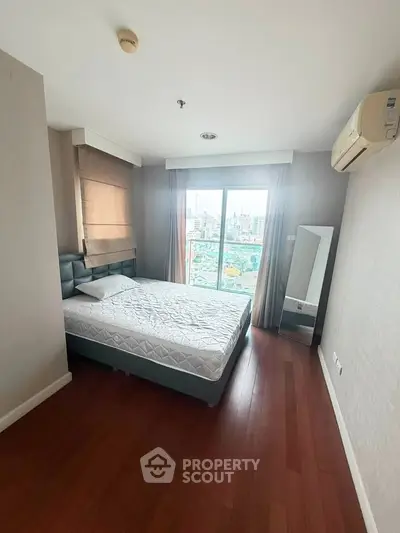 Spacious bedroom with city view, hardwood floors, and modern furnishings in a high-rise apartment.