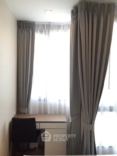 Cozy study nook with elegant curtains and sleek desk in a bright, modern apartment.