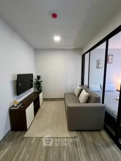 Modern living room with sleek design and cozy ambiance, featuring a wall-mounted TV and stylish furniture.