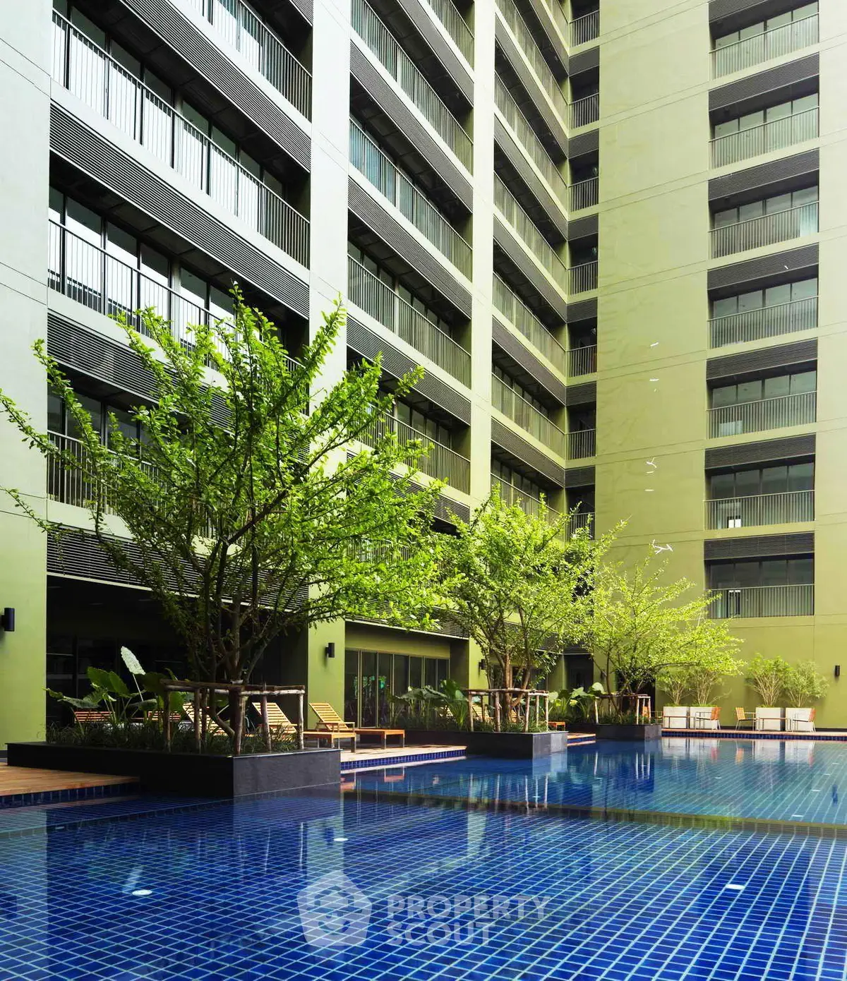 Luxurious apartment building with a stunning pool and lush greenery, perfect for relaxation and leisure.