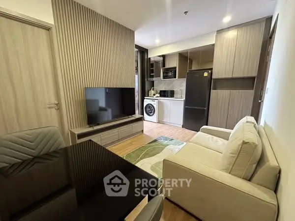 Modern living room with open kitchen, featuring sleek appliances and stylish decor.
