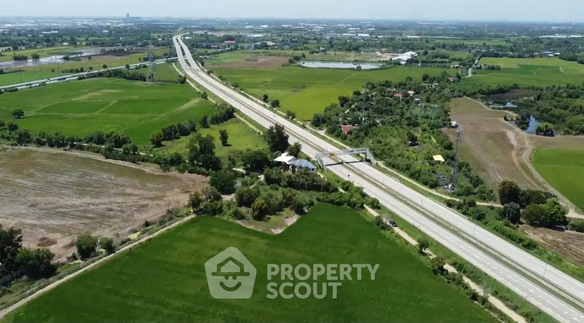 Scenic aerial view of expansive green fields and highway, perfect for real estate development opportunities.