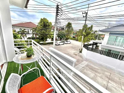 Charming balcony with outdoor seating and street view in a suburban neighborhood.
