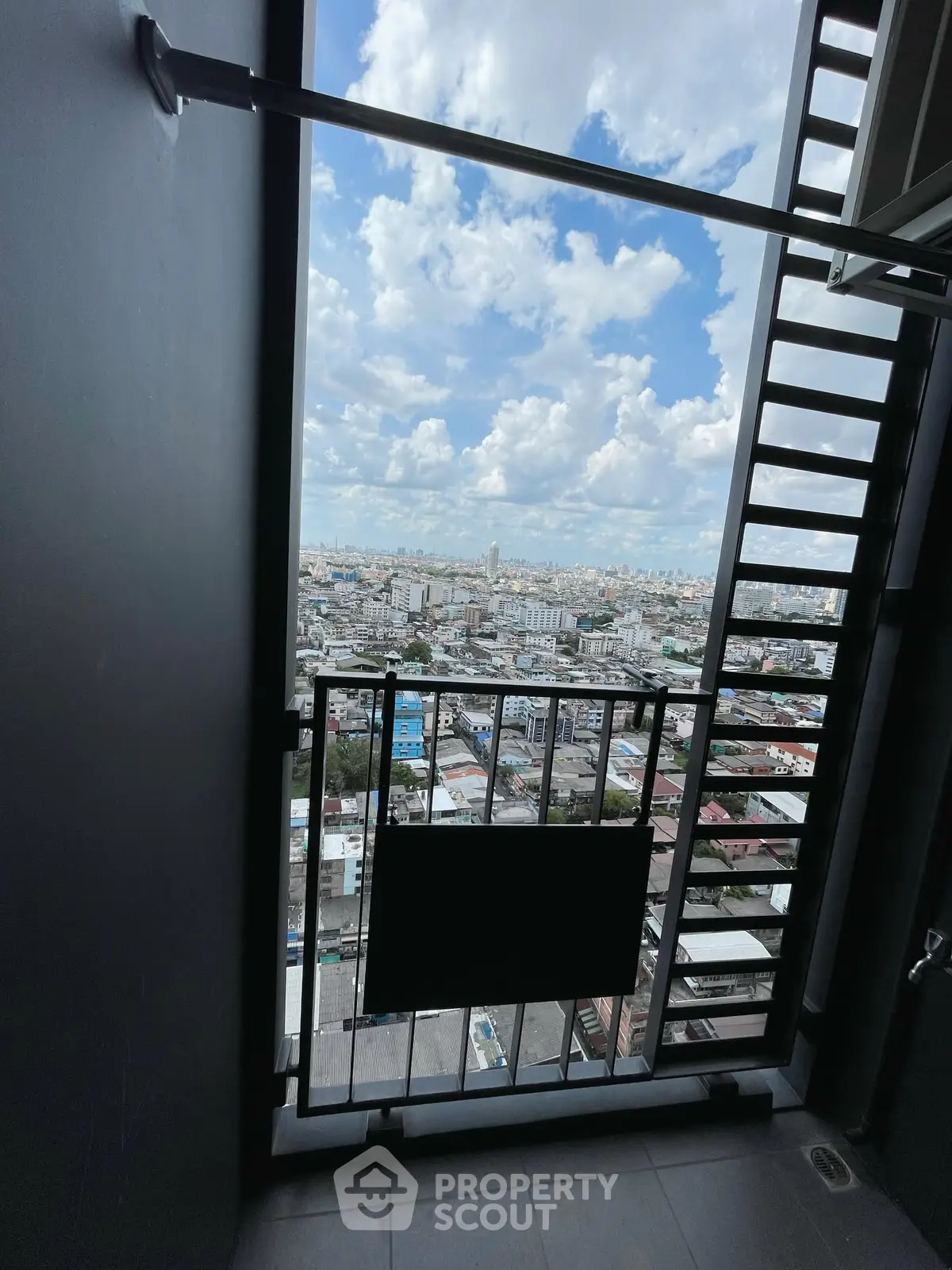 Stunning cityscape view from a high-rise balcony with clear skies and urban landscape.