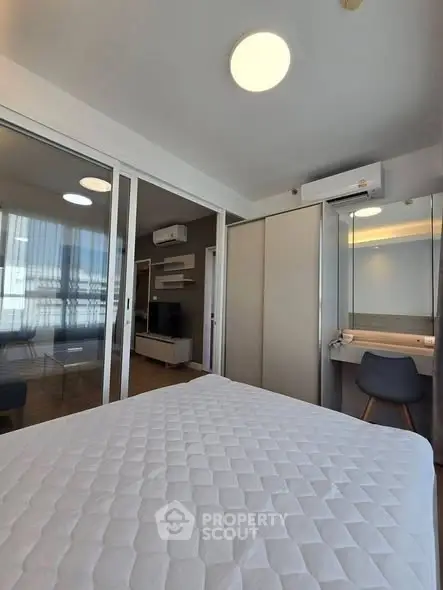 Modern bedroom with sliding glass doors and built-in closet, featuring a cozy workspace and air conditioning.
