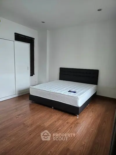 Spacious bedroom with modern bed and wooden flooring, perfect for comfort and style.