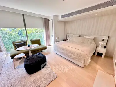 Luxurious bedroom with modern decor and large window overlooking greenery.