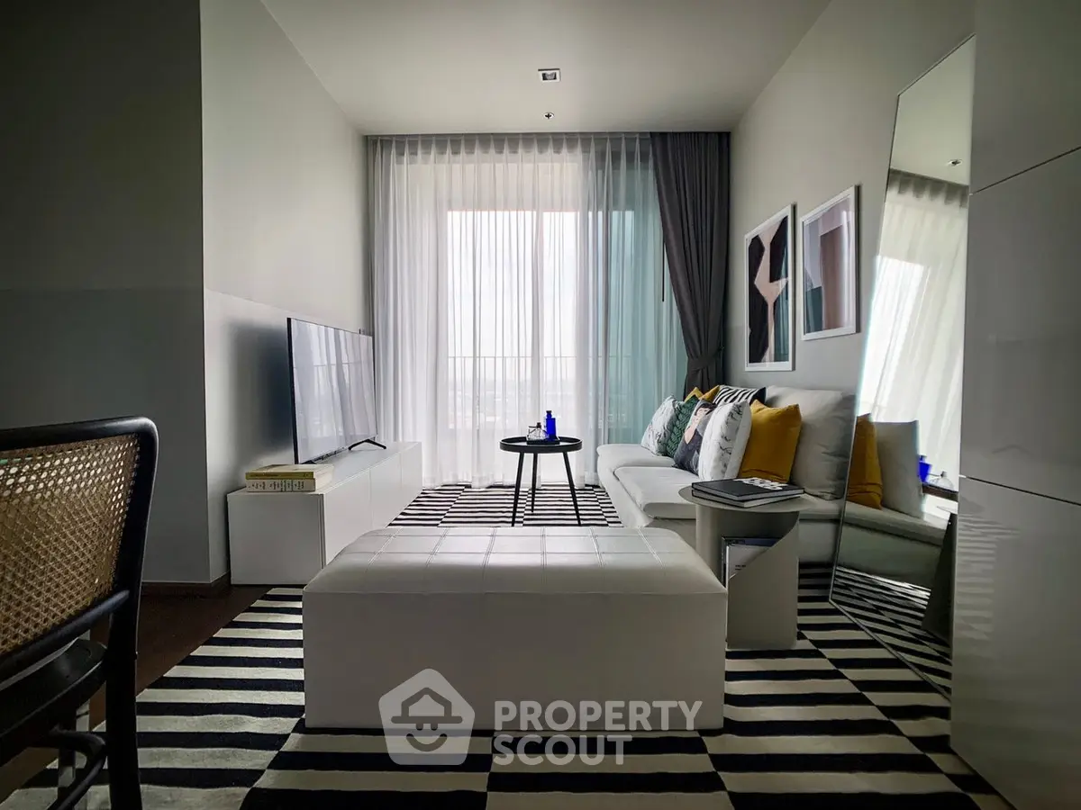 Modern living room with stylish decor, large TV, and natural light from floor-to-ceiling windows.