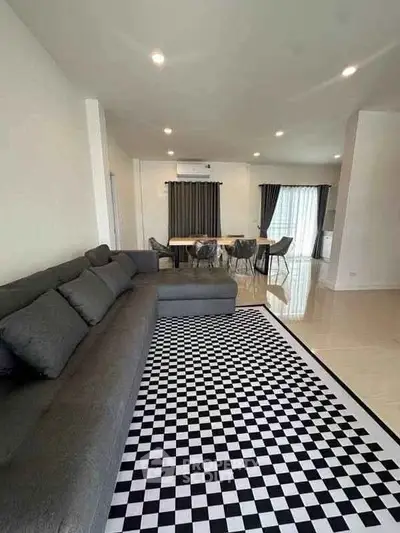 Spacious modern living room with stylish checkered rug and elegant dining area.