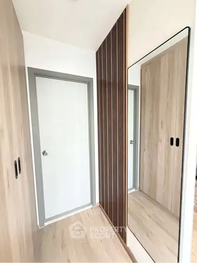 Modern hallway with sleek wooden paneling and large mirror reflecting minimalist design.
