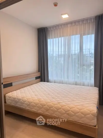 Modern bedroom with large window and stylish wooden bed frame in a bright apartment.