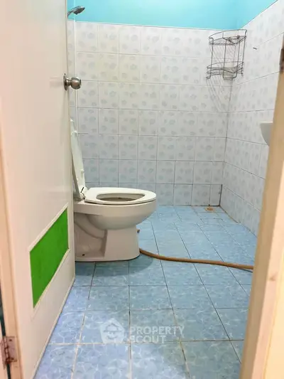 Compact bathroom with blue tiled floor and white fixtures, featuring a toilet and wall-mounted storage.