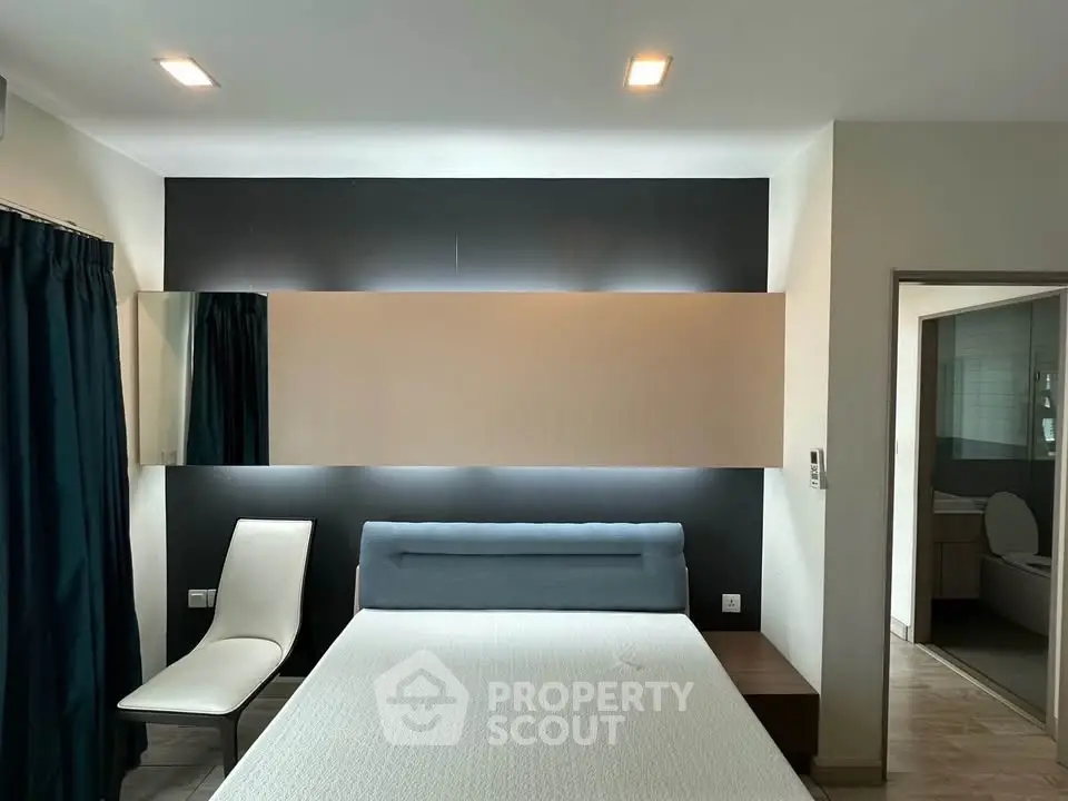 Modern bedroom with stylish lighting and elegant decor, featuring a comfortable bed and sleek chair.