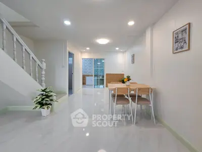 Spacious modern living area with dining set and elegant staircase, perfect for family gatherings.