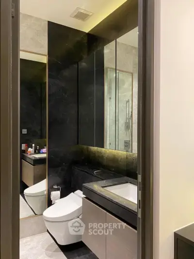 Luxurious modern bathroom with sleek black and gray design, featuring elegant fixtures and ambient lighting.