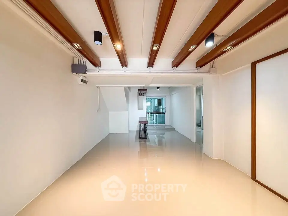 Spacious modern interior with sleek ceiling beams and glossy flooring, perfect for versatile living space.