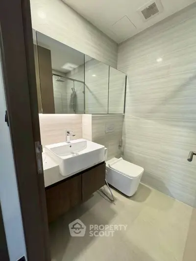 Modern bathroom with sleek fixtures and minimalist design, featuring a wall-mounted sink and toilet.