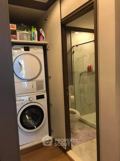 Compact laundry area with washer and dryer next to modern bathroom