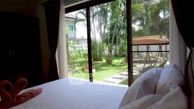 Spacious bedroom with garden view through large sliding glass doors, offering serene outdoor ambiance.