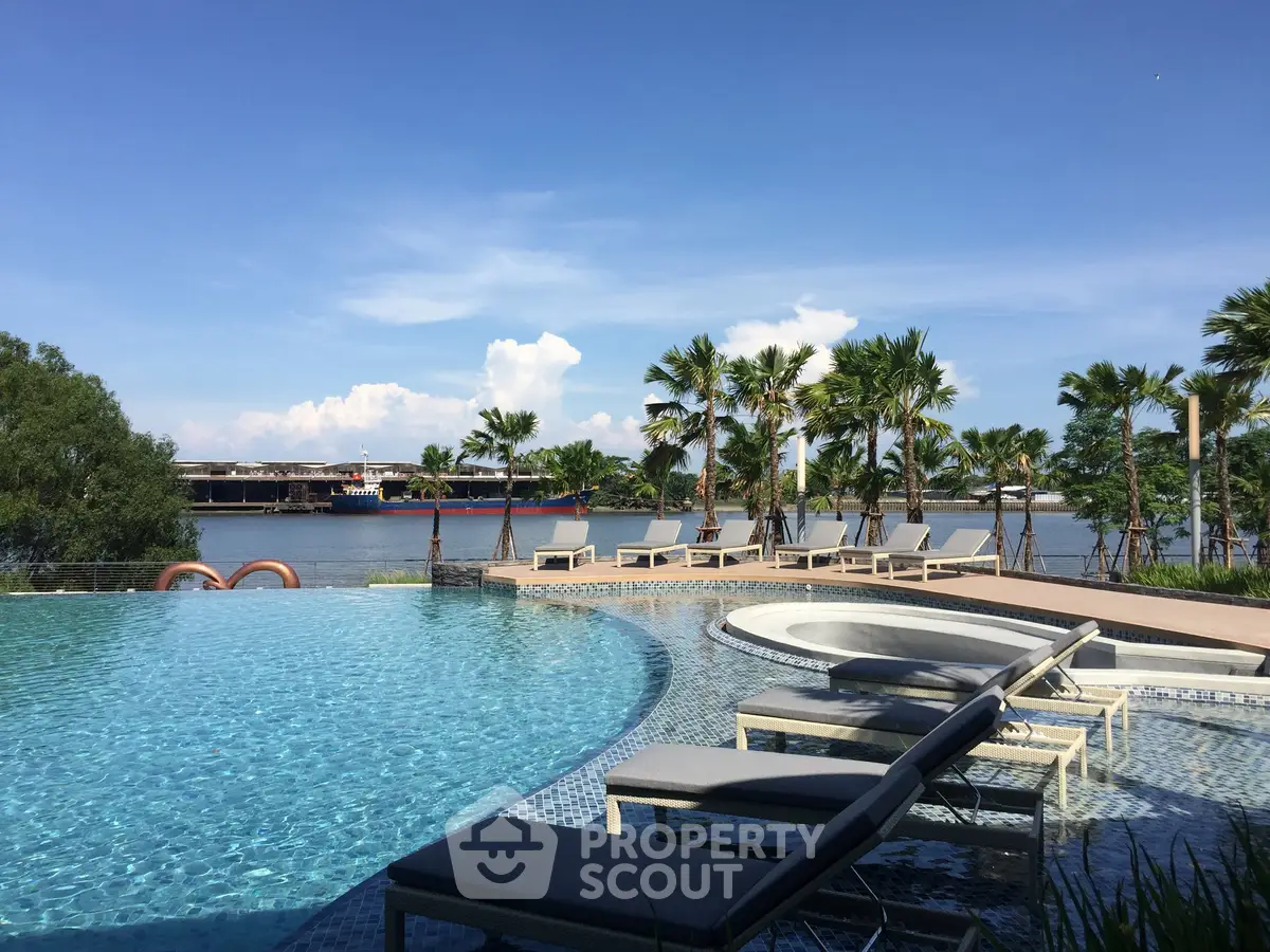 Luxurious riverside pool with sun loungers and palm trees, offering a serene escape and stunning water views.