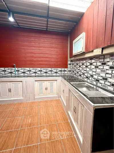 Charming kitchen with rustic red walls and modern tile backsplash, featuring ample cabinetry and stainless steel sink.