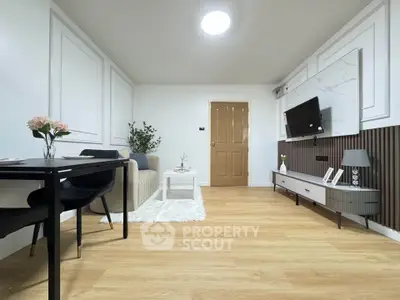 Modern living room with stylish decor and wall-mounted TV, featuring elegant furniture and wooden flooring.