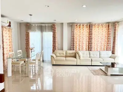 Spacious living room with elegant decor and natural light, featuring a cozy sofa and stylish dining area.