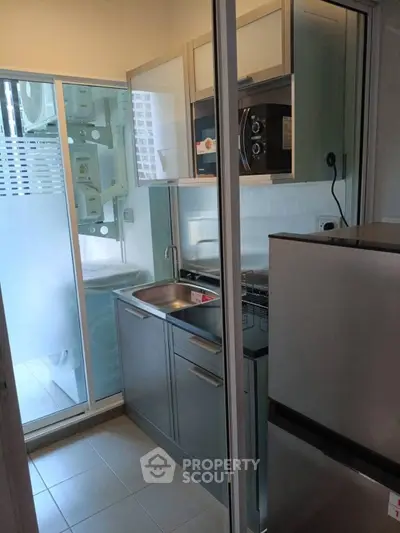Compact modern kitchen with stainless steel appliances and glass sliding door