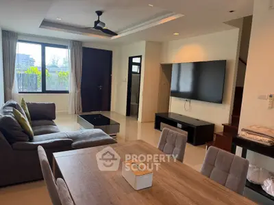 Spacious modern living room with large TV and stylish furniture, perfect for relaxation and entertainment.