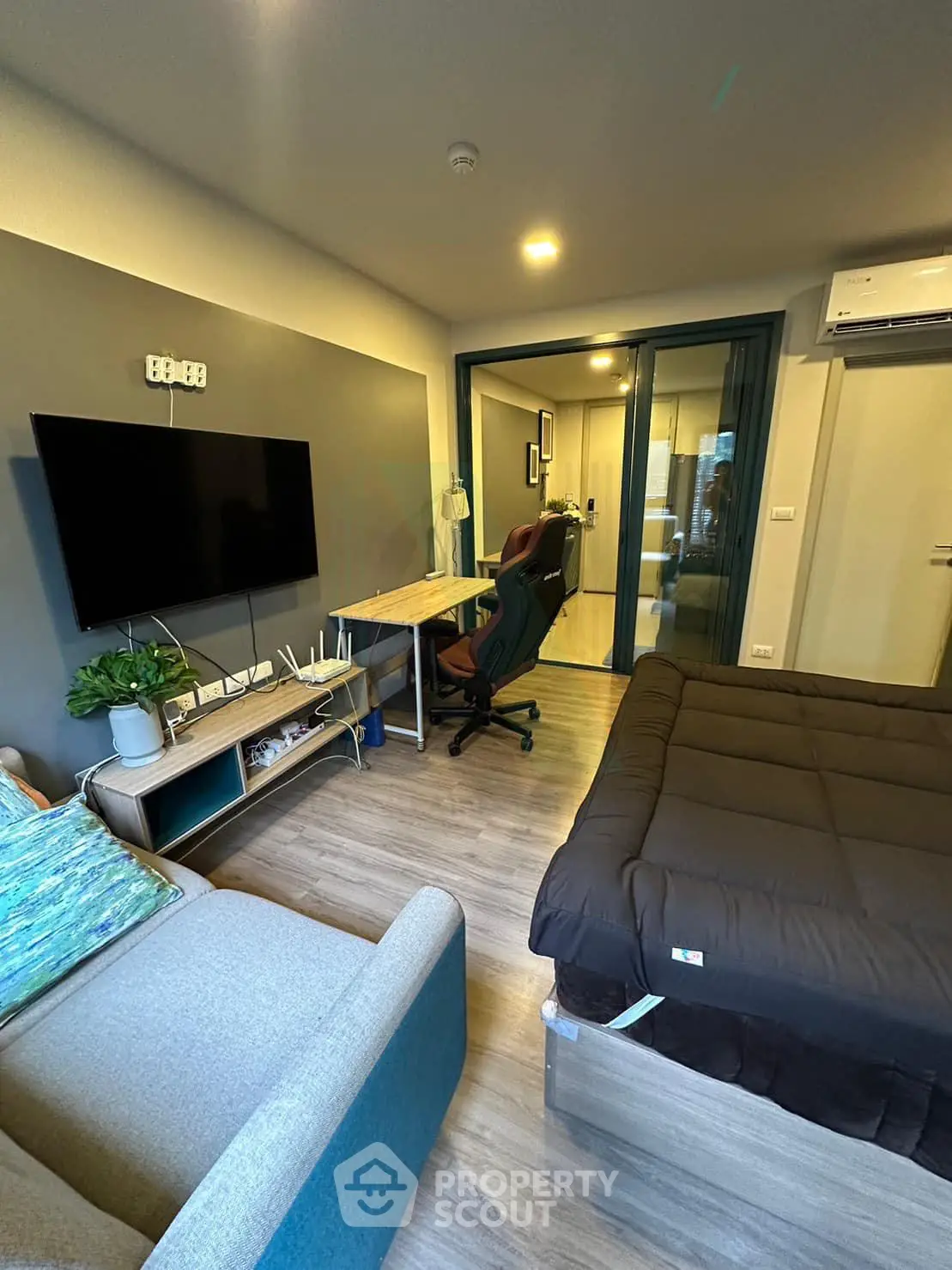 Modern studio apartment with cozy living area and workspace, featuring a wall-mounted TV and stylish decor.