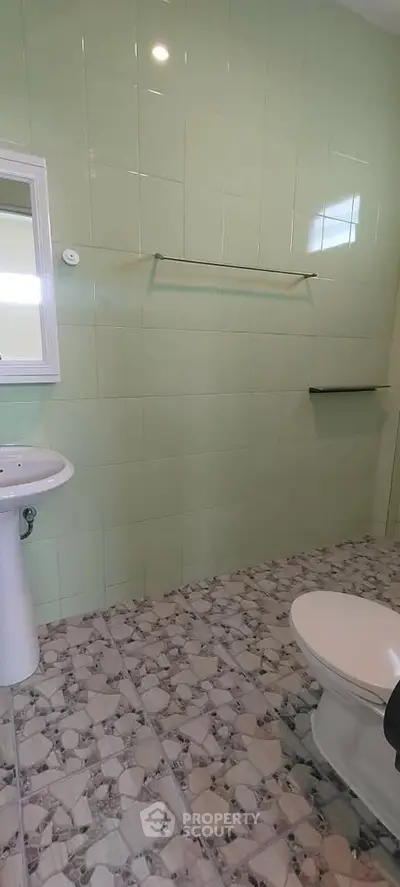 Spacious bathroom with green tiled walls and modern fixtures