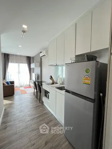 Modern kitchen with sleek appliances and open layout leading to cozy living area.