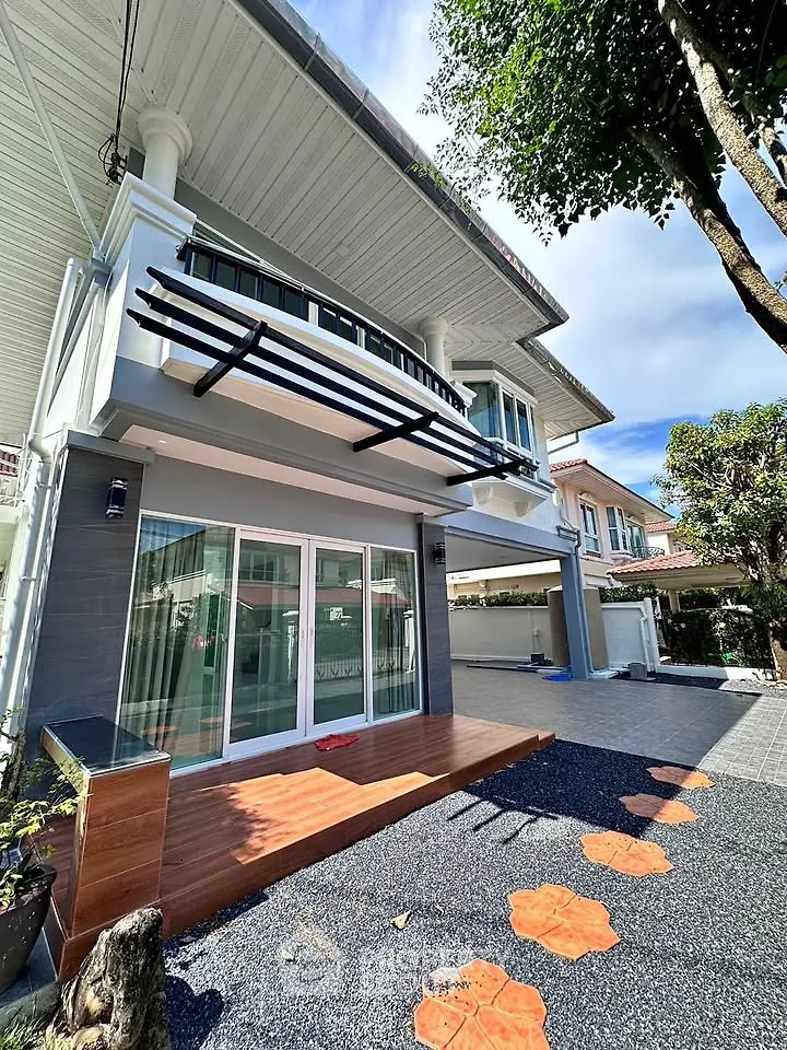 Modern two-story house with balcony and spacious driveway in a serene neighborhood.