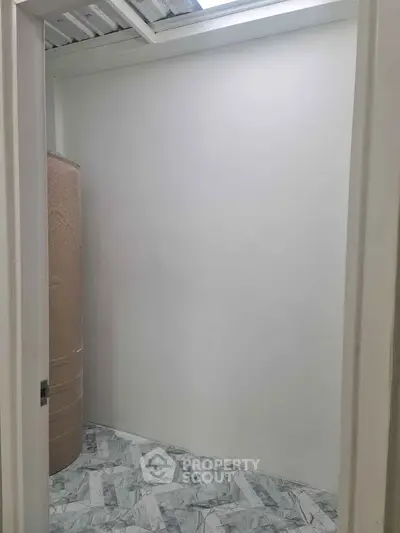 Compact storage room with tiled flooring and water tank