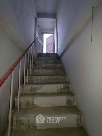 Concrete staircase leading to an open door with natural light, showcasing potential renovation opportunity.