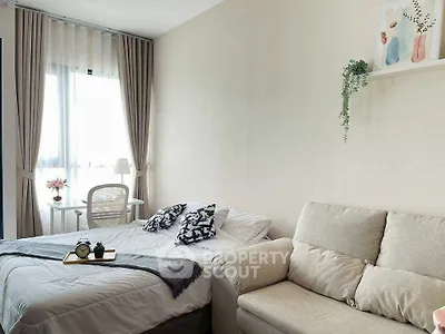 Cozy bedroom with natural light, stylish decor, and comfortable seating area.