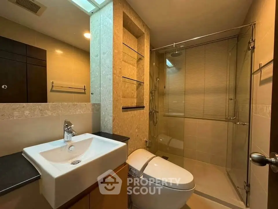 Modern bathroom with sleek fixtures and glass shower enclosure.