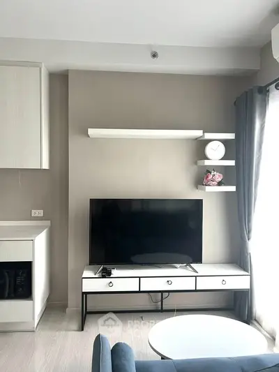 Modern living room with sleek TV setup and stylish shelving in a bright apartment.