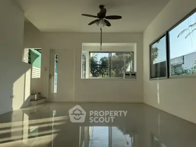 Spacious living room with large windows and ceiling fan, offering abundant natural light and modern design.